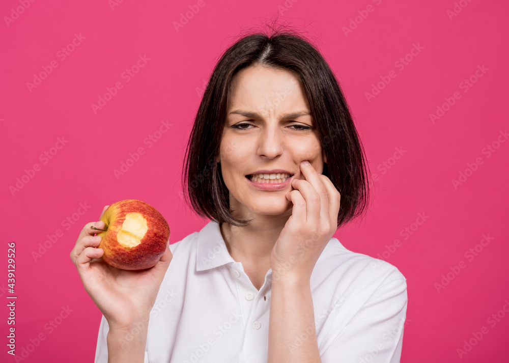 Beautiful young woman bites a big apple and has a toothache Beautiful young woman bites a big apple and has a toothache