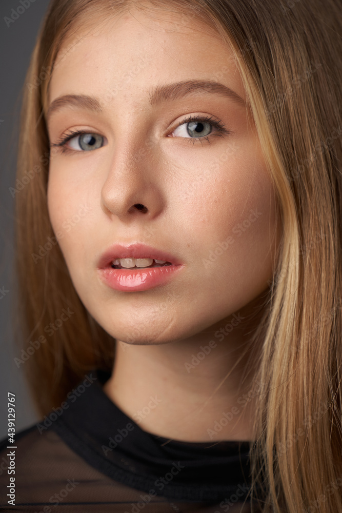 Natural portrait of young beautiful teen age girl with long straight hair. Female model studio shot against grey background. Pretty girl