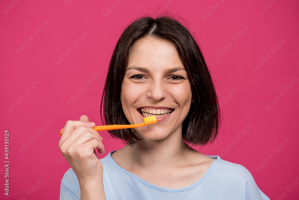 Beautiful happy young woman with toothbrush on blank pink background