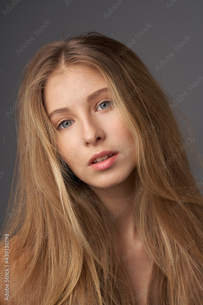 Fototapeta premium Natural portrait of young beautiful teen age girl with long straight hair. Female model studio shot against grey background. Pretty girl