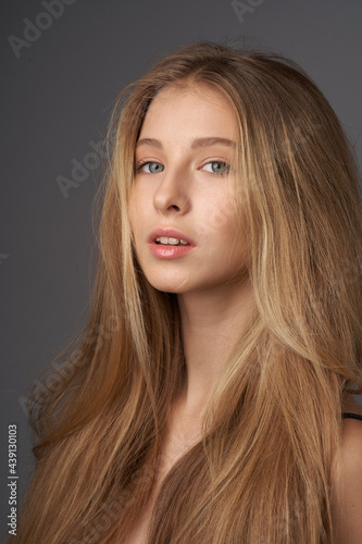 Natural portrait of young beautiful teen age girl with long straight hair. Female model studio shot against grey background. Pretty girl
