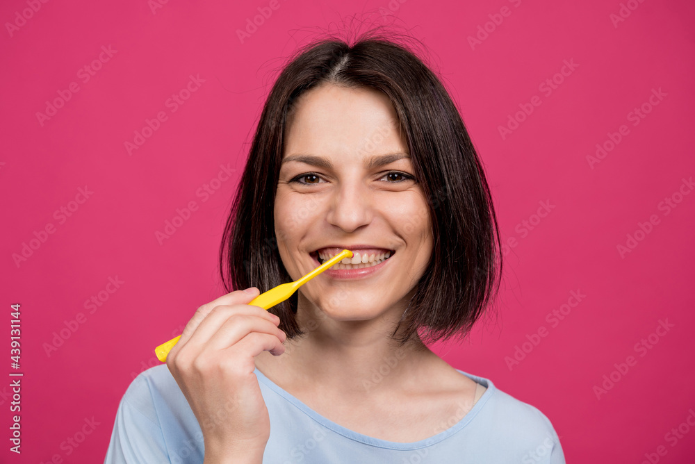 Beautiful happy young woman with single tufted toothbrush on blank pink background Beautiful happy young woman with single tufted toothbrush on blank pink background