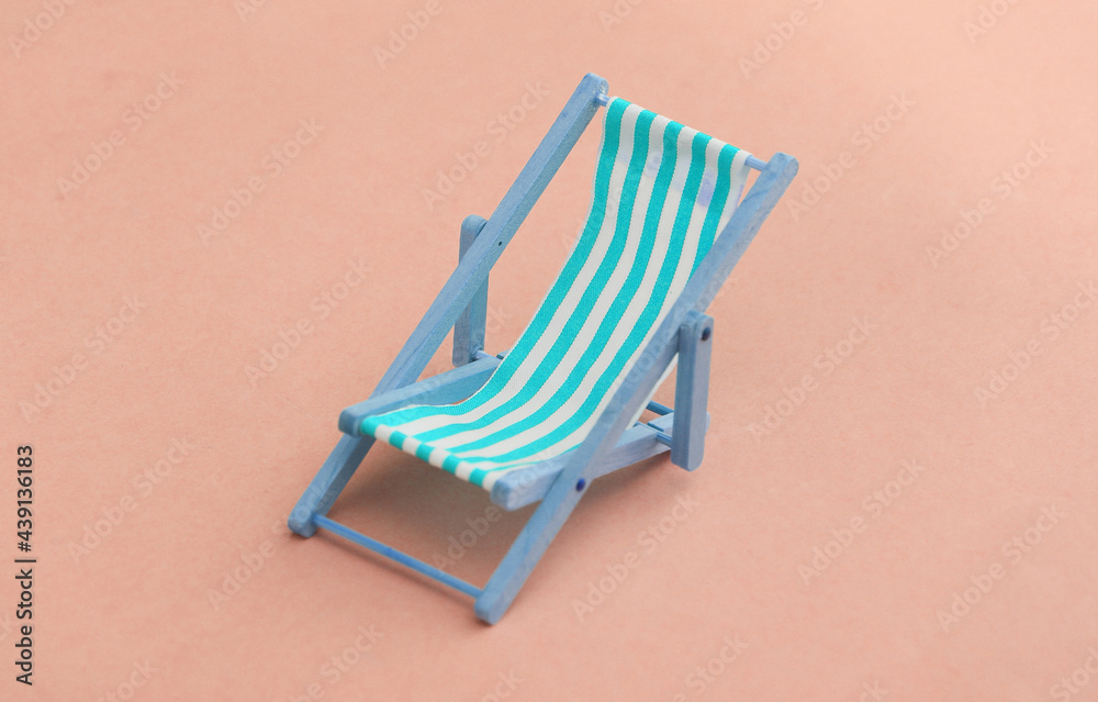 Striped mini beach deck chair on pink background. Symbol of beach holidays, resort.  Relax, Summer minimal concept
