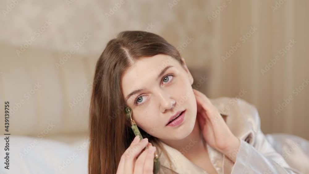 Portrait of an adult girl doing a facial massage with a jade roller Portrait of an adult girl doing a facial massage with a jade roller