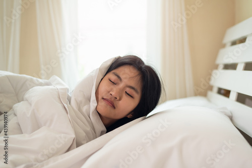 Young Asian woman lying on pillow in bed with blanket
