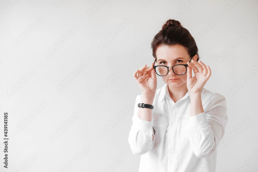 Portrait of a serious beautiful woman in optical glasses and a white shirt on a white background. Copy, empty space for text Portrait of a serious beautiful woman in optical glasses and a white shirt on a white background. Copy, empty space for text