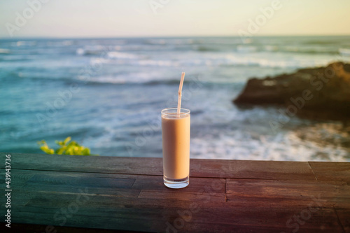 A delicious sweet milkshake on a wooden bar at beautiful seaside.