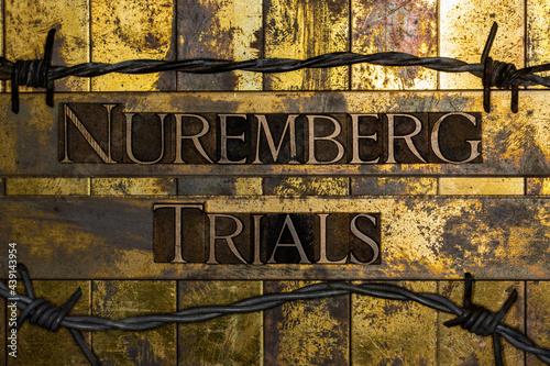 Nuremberg Trials text on vintage textured grunge copper and gold bar background surrounded by barbed wire