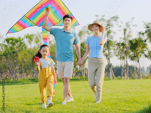 Happy family of three flying kites in the park