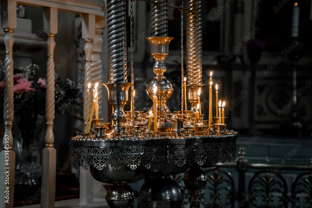 Several long thin candles burn in the darkness of an orthodox church (849)