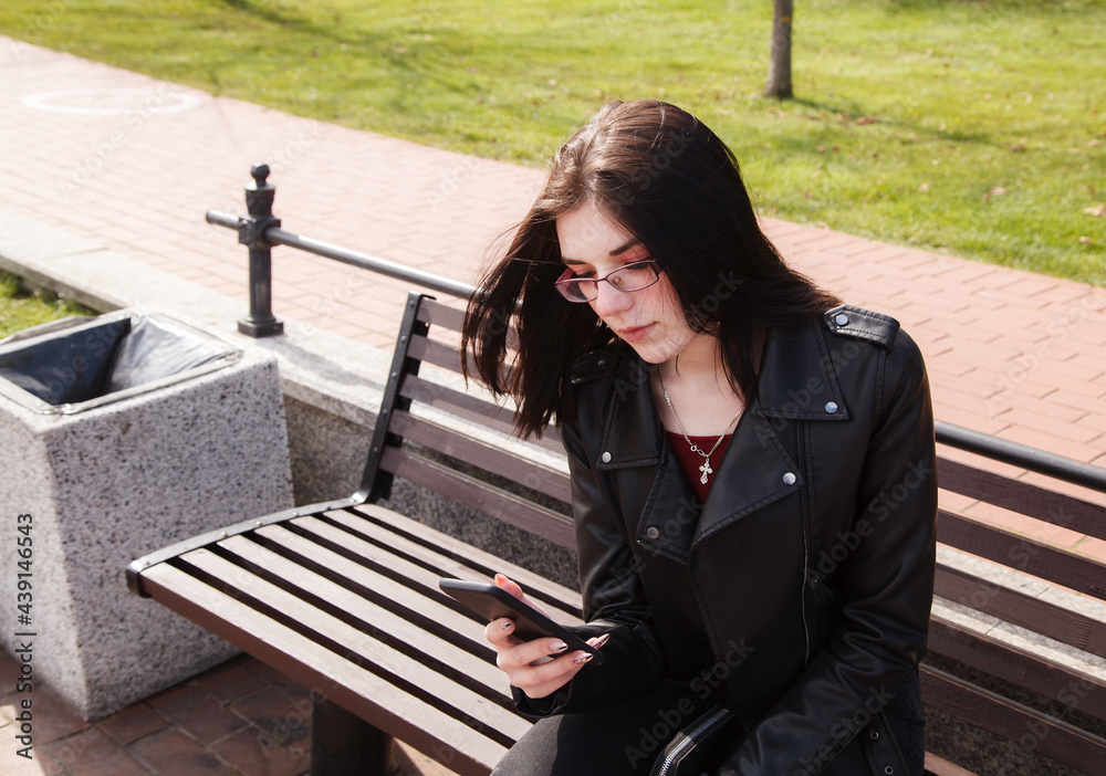 young girl looking at smartphone display while sitting on bench