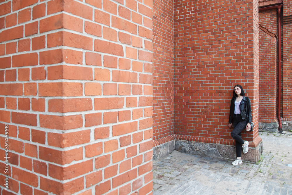 young girl stands near the wall of a gothic church