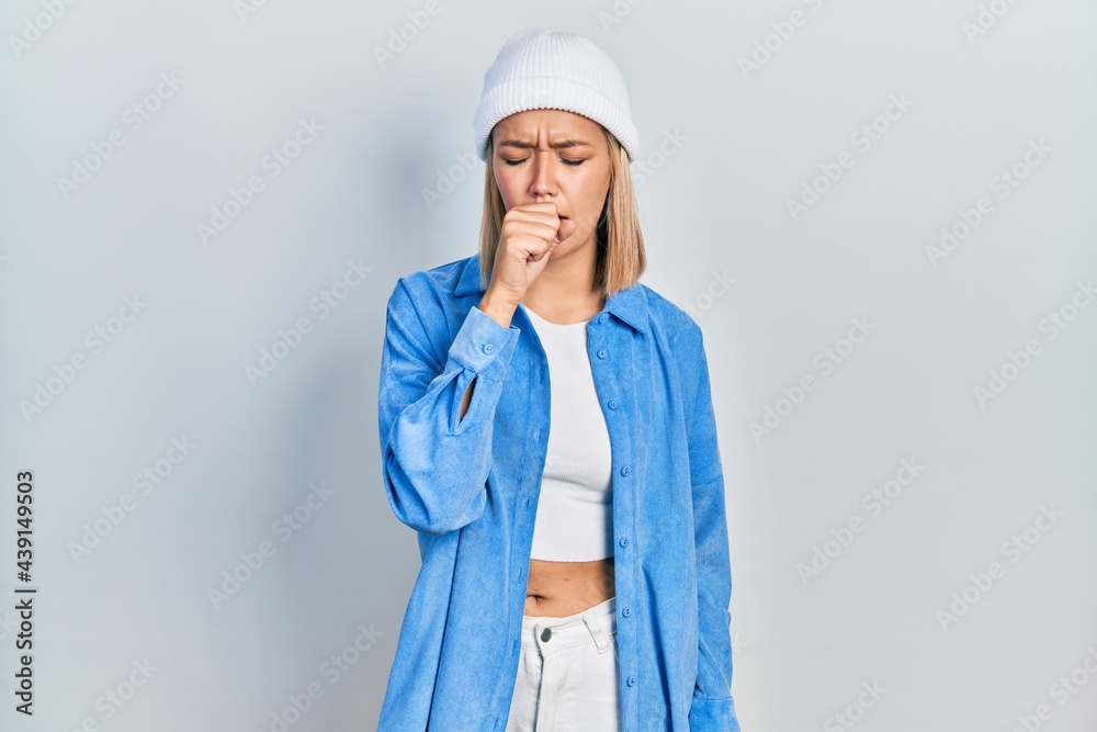Beautiful blonde woman wearing wool hat feeling unwell and coughing as symptom for cold or bronchitis. health care concept. Beautiful blonde woman wearing wool hat feeling unwell and coughing as symptom for cold or bronchitis. health care concept.