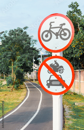 Bicycle route signs and signs prohibiting cars and motorcycles passing with a bicycle lane background.