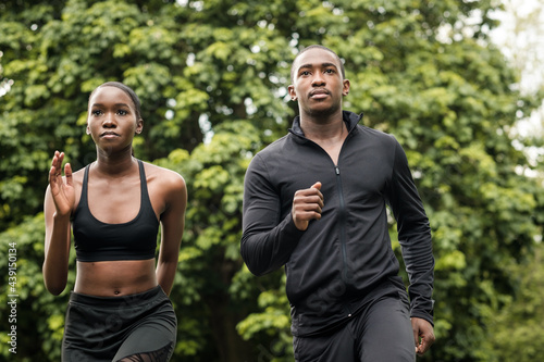 Black brother and sister twins running outdoors in stylish sportswear.