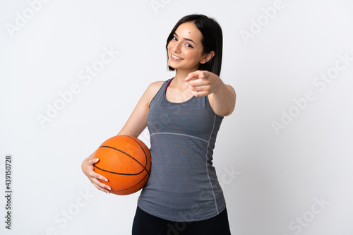 Young woman playing basketball isolated on white background pointing front with happy expression