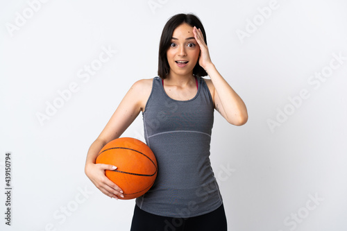 Young woman playing basketball isolated on white background with surprise expression