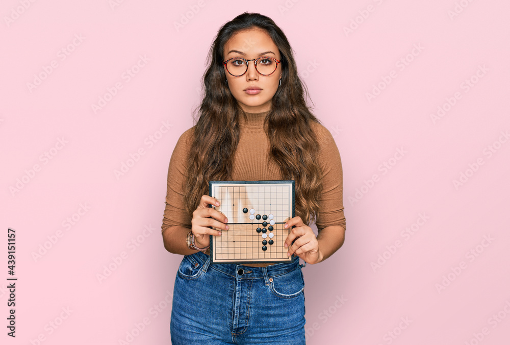 Young hispanic girl holding drauhgts thinking attitude and sober expression looking self confident Young hispanic girl holding drauhgts thinking attitude and sober expression looking self confident