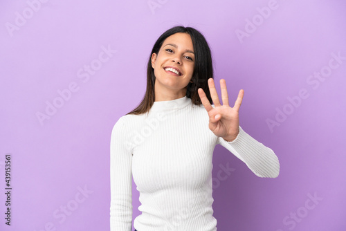 Young caucasian woman isolated on purple background happy and counting four with fingers