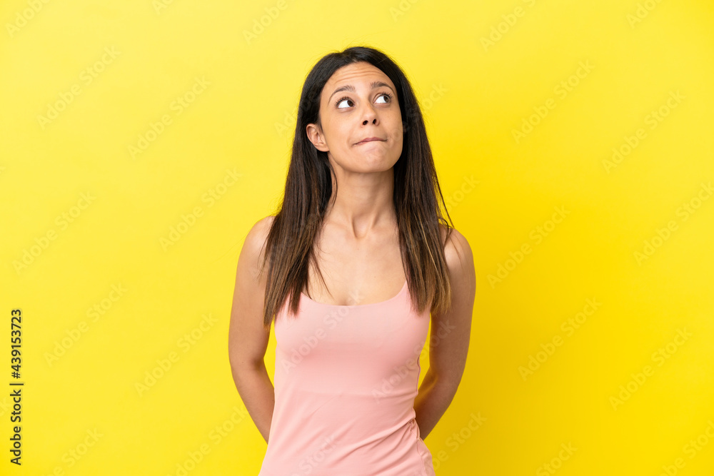 Young caucasian woman isolated on yellow background and looking up Young caucasian woman isolated on yellow background and looking up