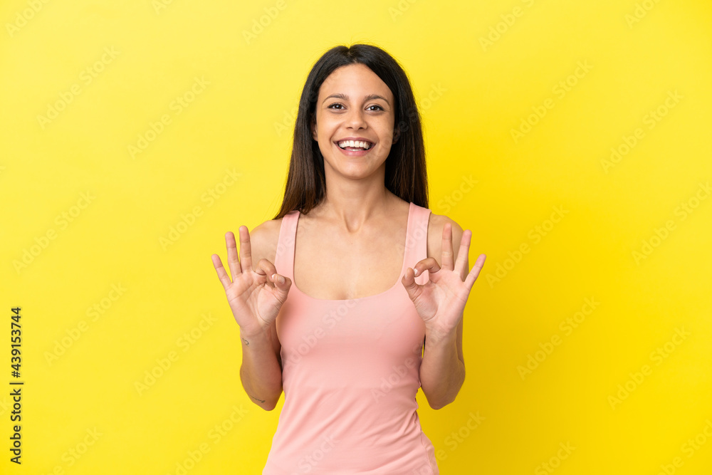 Young caucasian woman isolated on yellow background showing ok sign with two hands Young caucasian woman isolated on yellow background showing ok sign with two hands