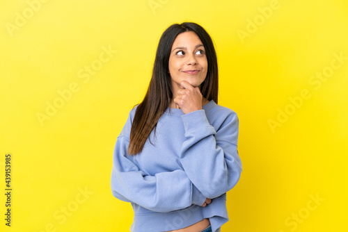 Young caucasian woman isolated on yellow background thinking an idea while looking up © luismolinero