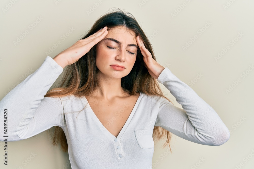 Young caucasian woman wearing casual white t shirt with hand on head, headache because stress. suffering migraine. Young caucasian woman wearing casual white t shirt with hand on head, headache because stress. suffering migraine.