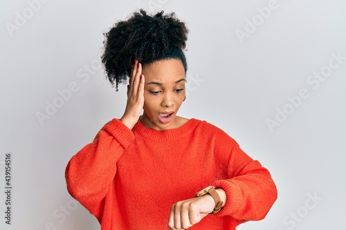 Young african american girl wearing casual clothes looking at the watch time worried, afraid of getting late
