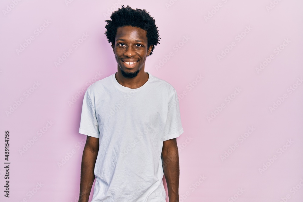 Young african american man wearing casual white t shirt with a happy and cool smile on face. lucky person. Young african american man wearing casual white t shirt with a happy and cool smile on face. lucky person.