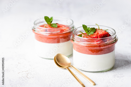 Panna cotta in glass jars with strawberry sauce and mint. photo