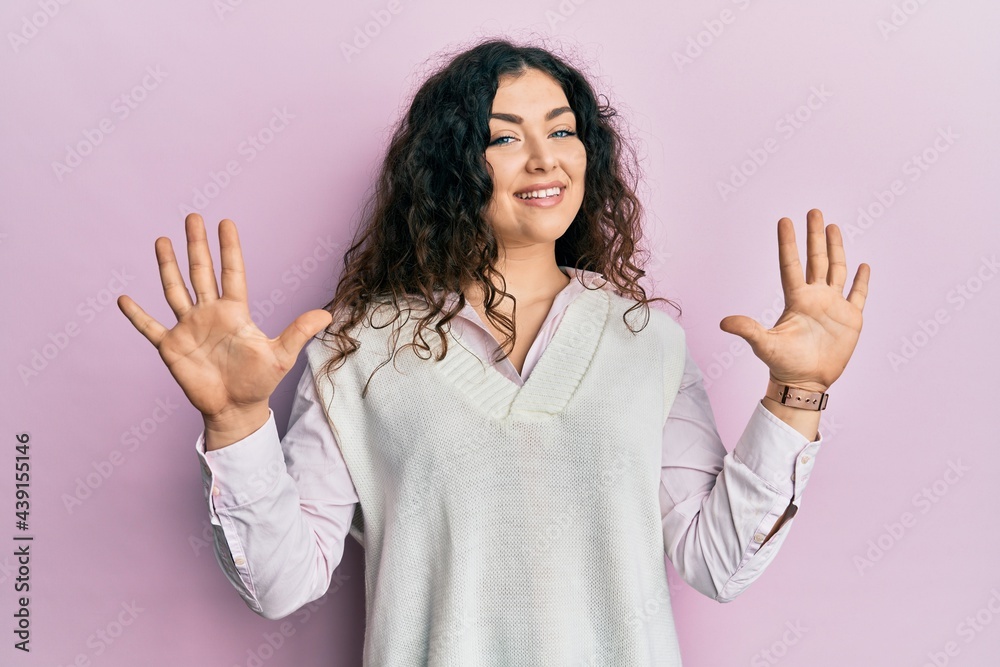Young brunette woman with curly hair wearing casual clothes showing and pointing up with fingers number ten while smiling confident and happy. Young brunette woman with curly hair wearing casual clothes showing and pointing up with fingers number ten while smiling confident and happy.