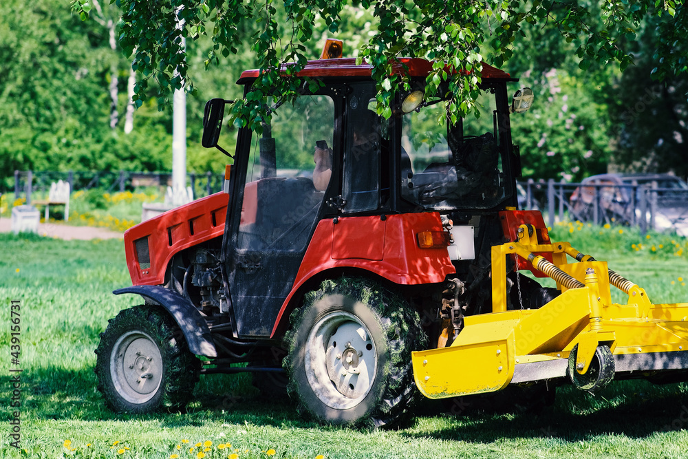 A small tractor mows the lawn. Landscaping of the area between the houses. City garden. A small tractor mows the lawn. Landscaping of the area between the houses. City garden.