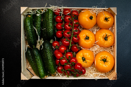 Delivery of fresh tomatoes and cucumbers in a wooden box