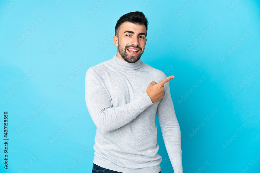 Caucasian man over isolated blue background surprised and pointing side
