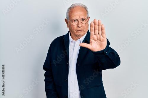Senior man with grey hair wearing casual style and glasses doing stop sing with palm of the hand. warning expression with negative and serious gesture on the face. © Krakenimages.com