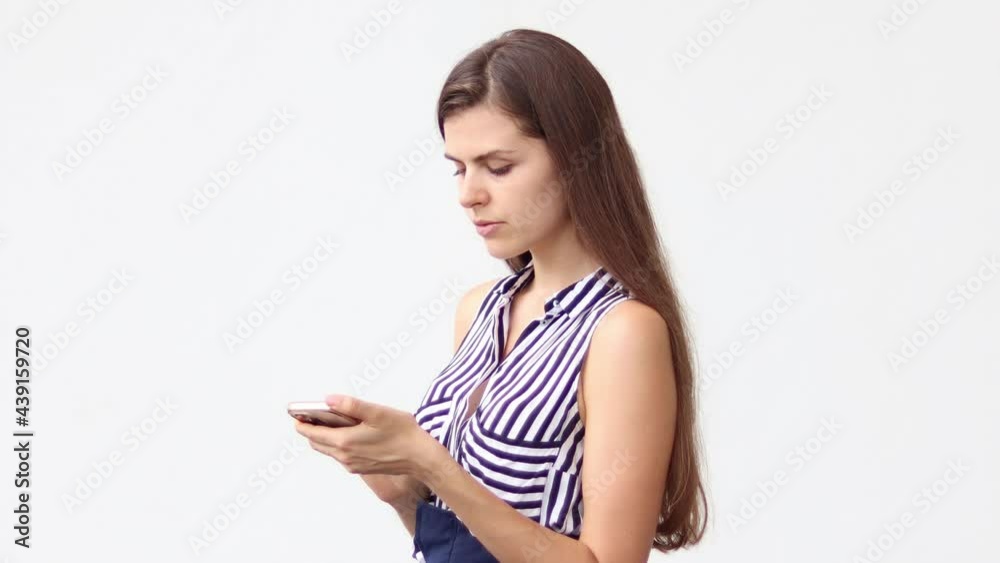 Happy casual woman checking smart phone on line content standing on white background. Happy woman enjoying spending time in social network. Happy casual woman checking smart phone on line content standing on white background. Happy woman enjoying spending time in social network.
