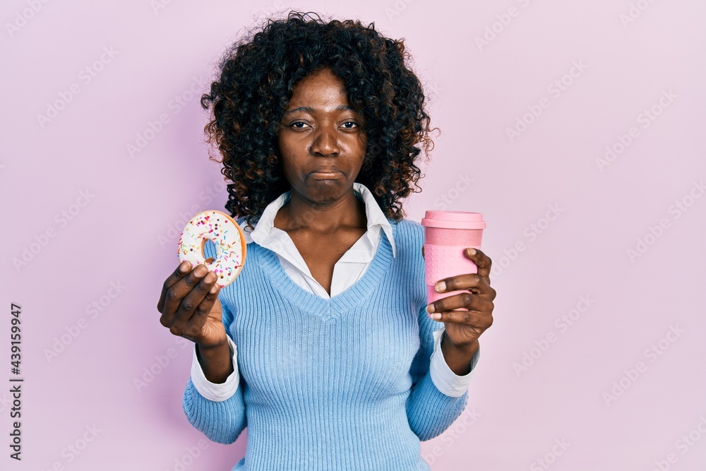 Young african american woman eating doughnut and drinking coffee depressed and worry for distress, crying angry and afraid. sad expression. Young african american woman eating doughnut and drinking coffee depressed and worry for distress, crying angry and afraid. sad expression.