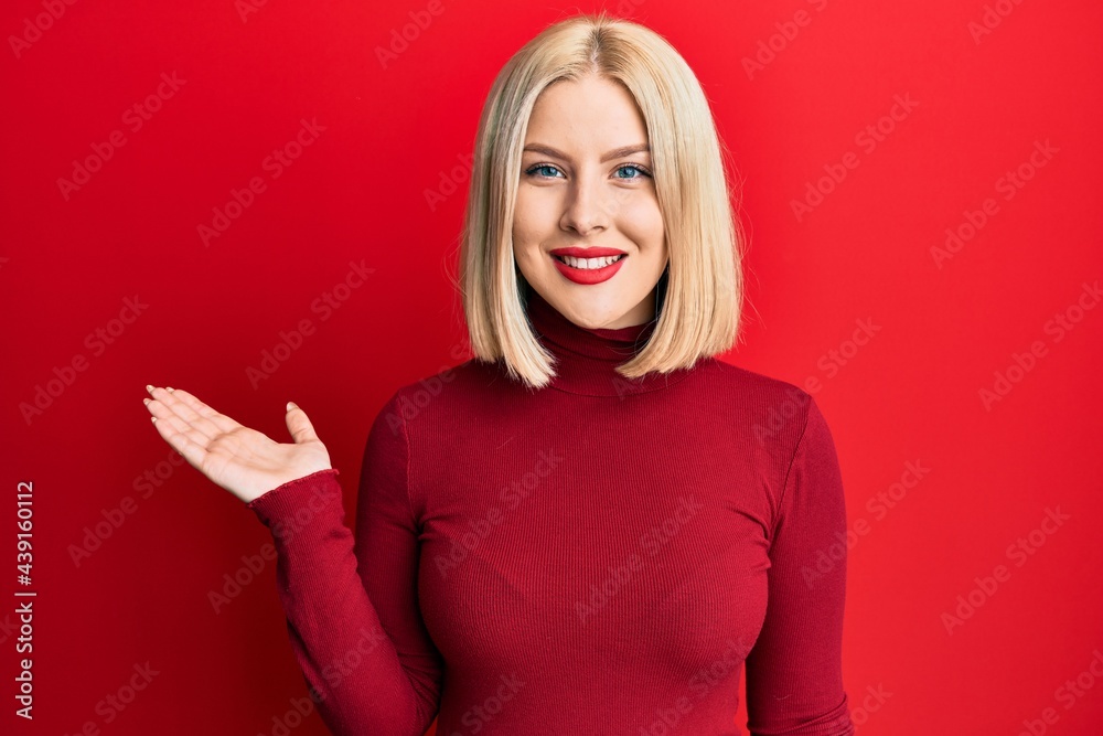 Young blonde woman wearing casual clothes smiling cheerful presenting and pointing with palm of hand looking at the camera. Young blonde woman wearing casual clothes smiling cheerful presenting and pointing with palm of hand looking at the camera.