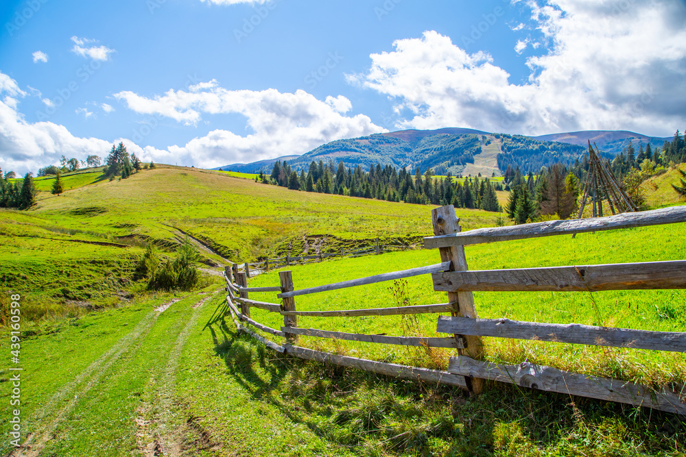 country road near wooden fence against mountains and forests background. Countryside