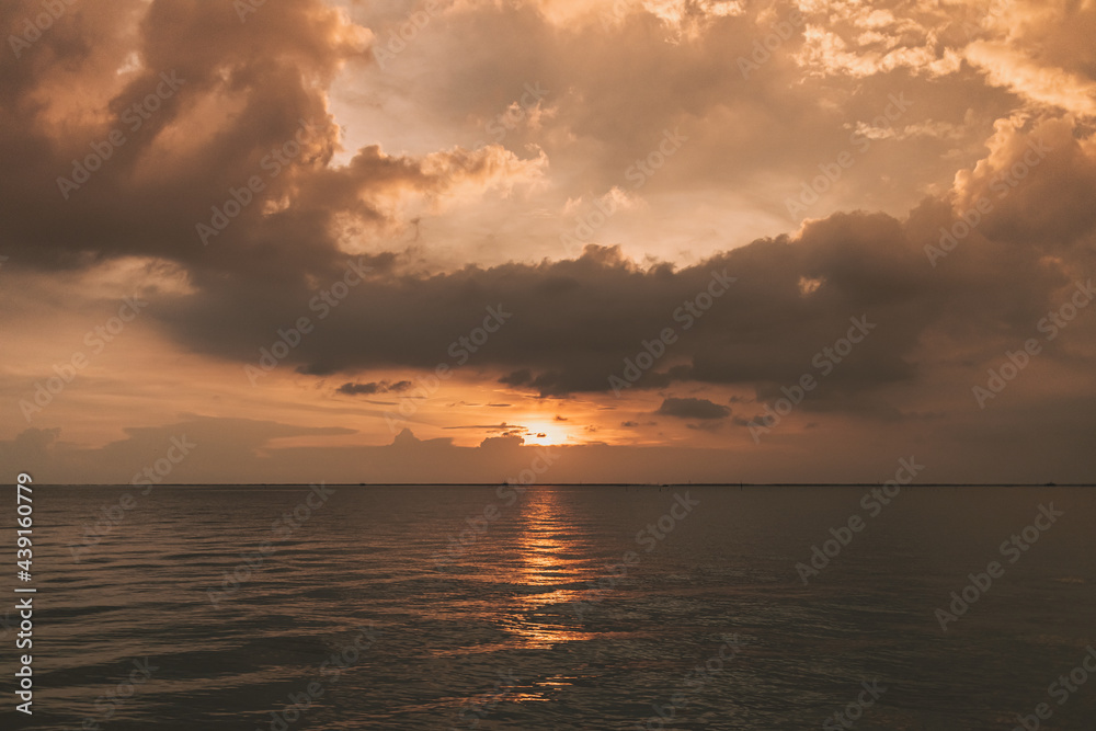 Calm sunset ocean with stormy cloud in the sky.