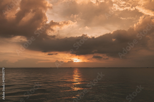 Calm sunset ocean with stormy cloud in the sky. © Sevendeman
