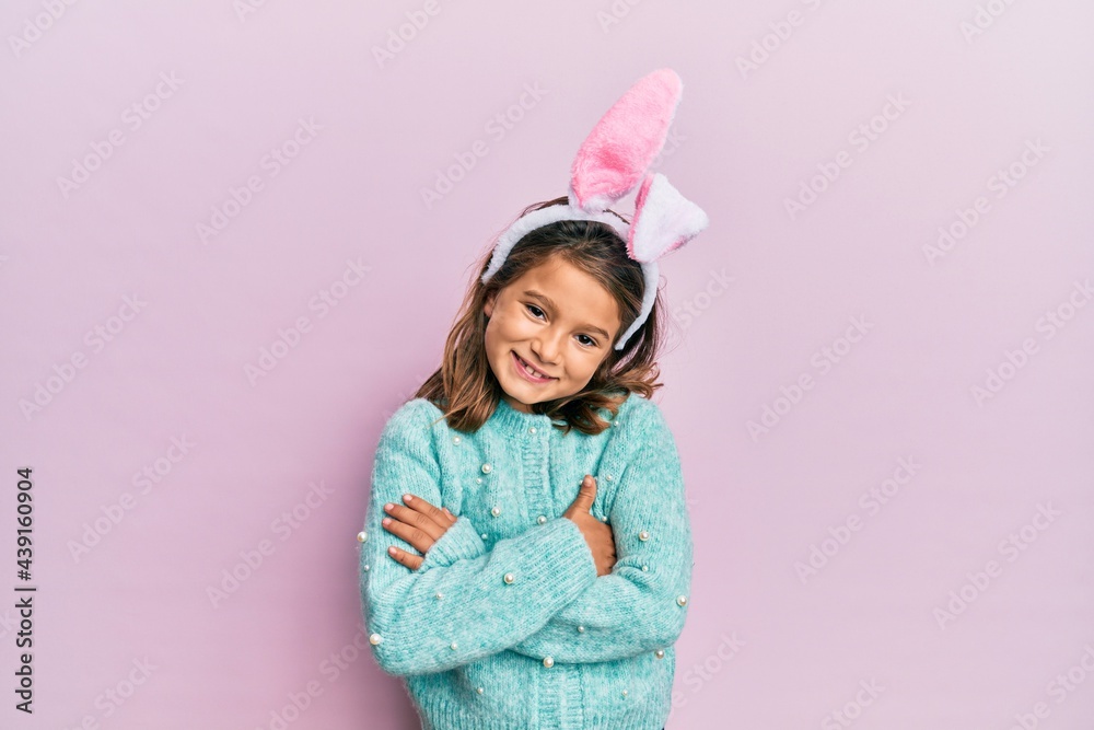Little beautiful girl wearing cute easter bunny ears happy face smiling with crossed arms looking at the camera. positive person. Little beautiful girl wearing cute easter bunny ears happy face smiling with crossed arms looking at the camera. positive person.