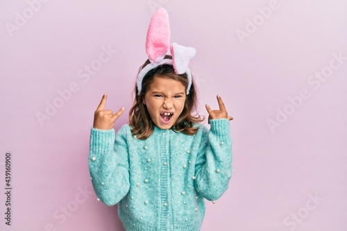 Canvas Print Little beautiful girl wearing cute easter bunny ears shouting with crazy expression doing rock symbol with hands up