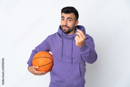 Man playing basketball over isolated white wall making money gesture © luismolinero