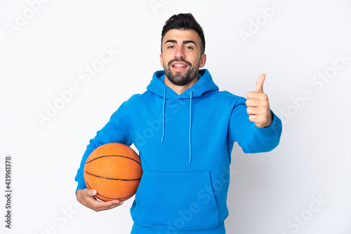 Caucasian man over isolated white background playing basketball and with thumb up © luismolinero
