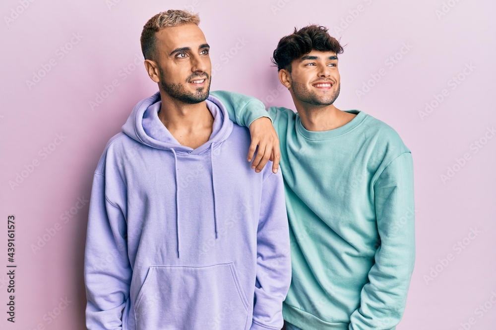 Homosexual gay couple standing together wearing casual clothes looking away to side with smile on face, natural expression. laughing confident. Homosexual gay couple standing together wearing casual clothes looking away to side with smile on face, natural expression. laughing confident.
