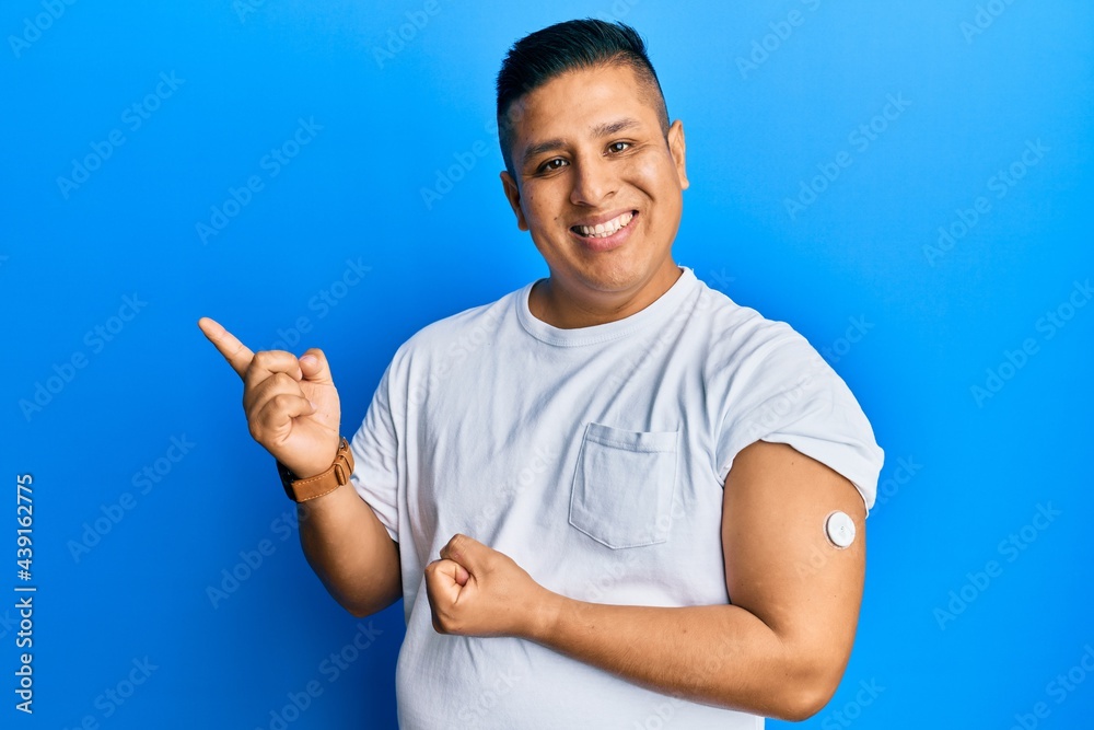 Young latin man using glucose meter button smiling happy pointing with hand and finger to the side Young latin man using glucose meter button smiling happy pointing with hand and finger to the side