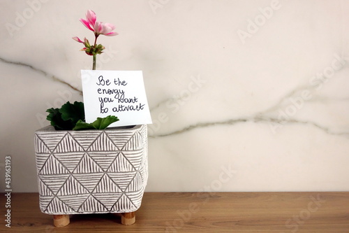 Be the energy you want to attract text handwritten on sticky note with fresh blossoming flower
