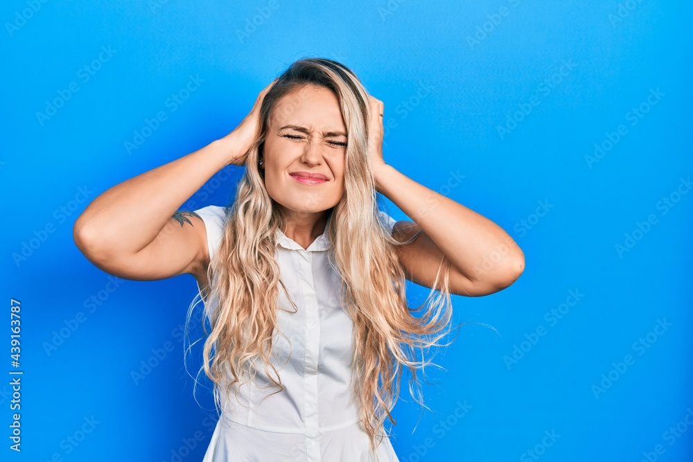 Beautiful young blonde woman wearing casual white shirt suffering from headache desperate and stressed because pain and migraine. hands on head.