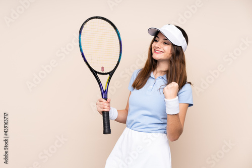 Young caucasian woman isolated on beige background playing tennis and celebrating a victory © luismolinero